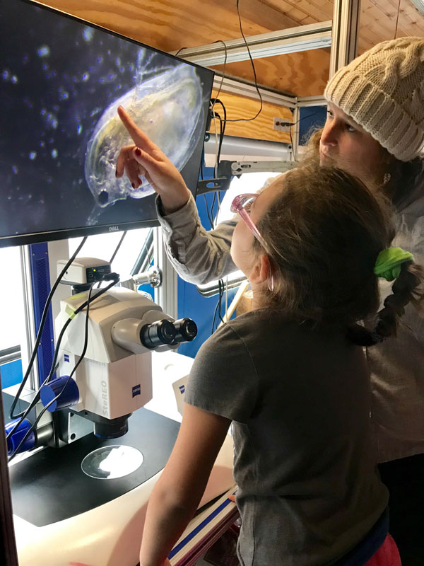 Photo of young student looking at microscopic plankton under a microscope