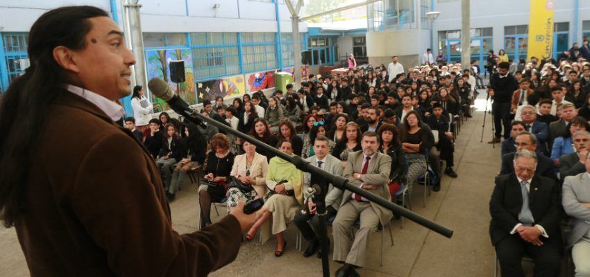 Photo of man on stage speaking to full audience