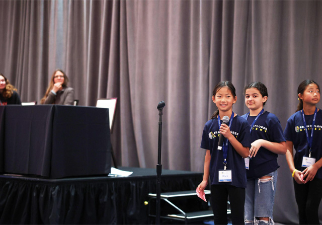 Photo of young students speaking on stage at science conference