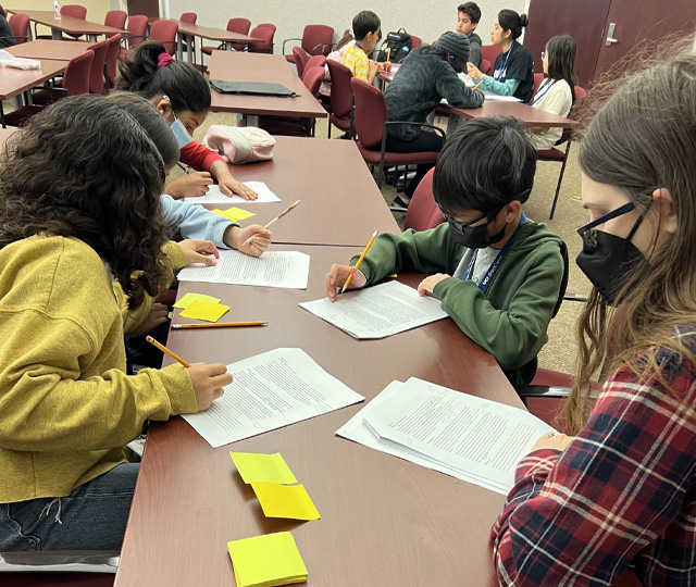 Photo of young students working at a large desk