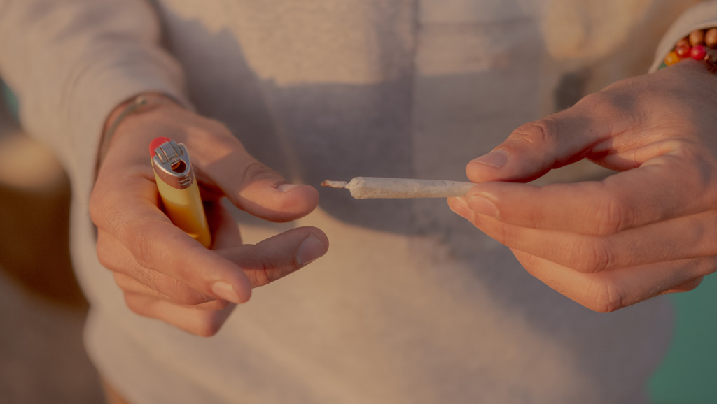 Closeup photo of young person holding a rolled cigarette and lighter