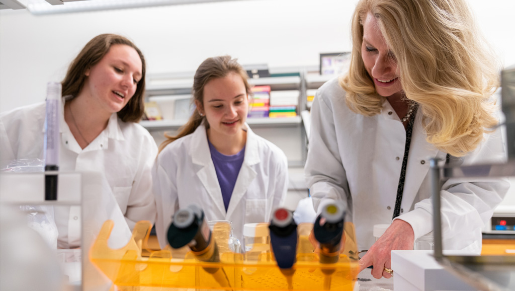 Scientist and two young students in a research lab