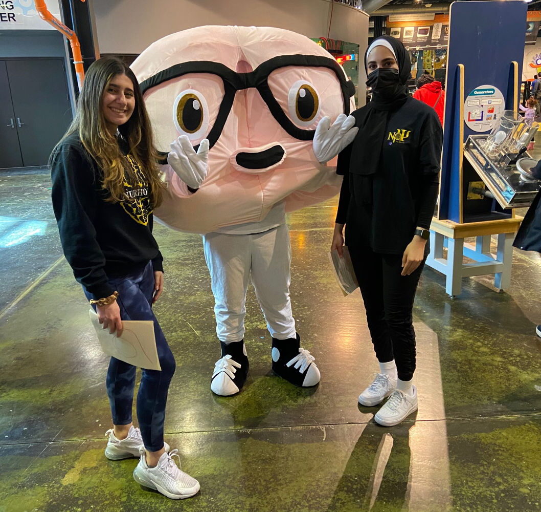 People standing next to a brain mascot