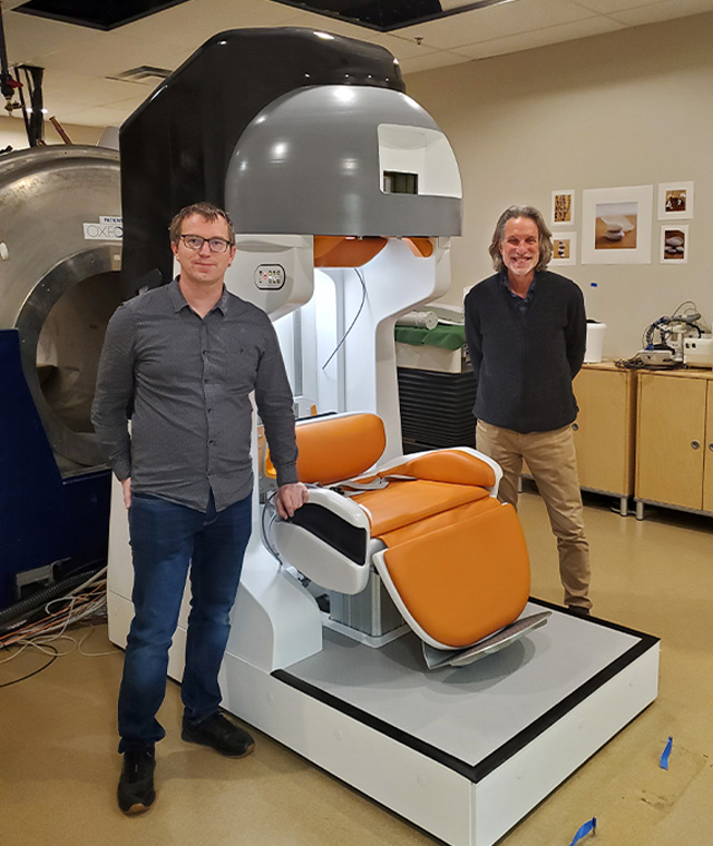 two researchers standing next to portable MRI