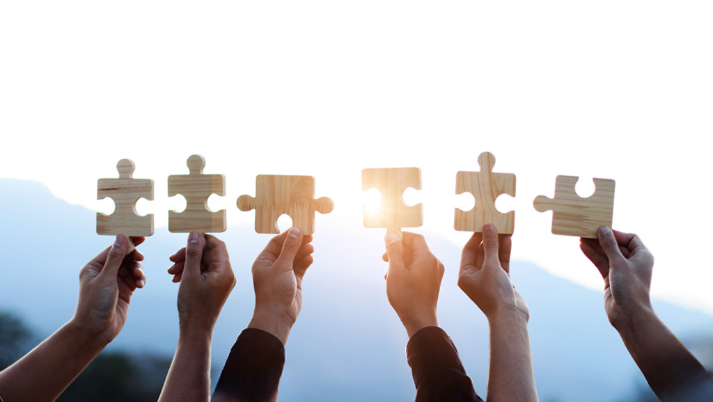 hands holding up wooden jigsaw pieces